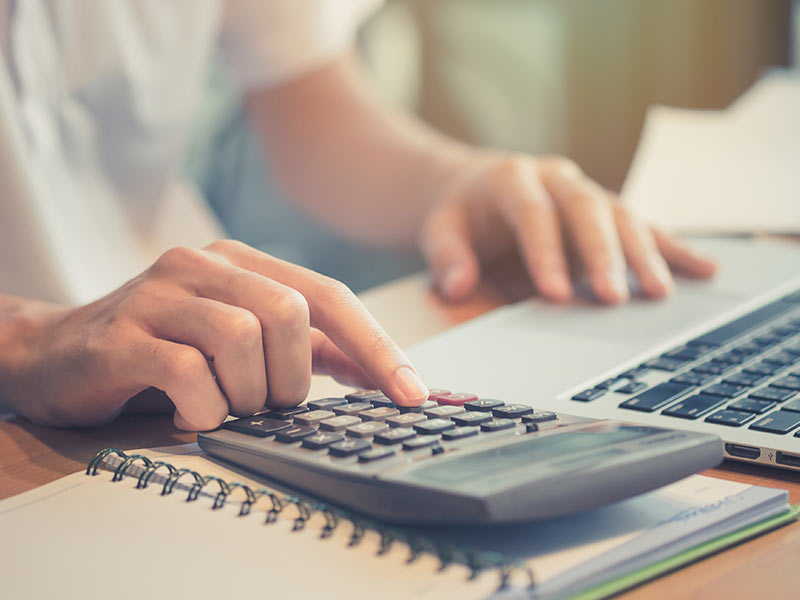 person at desk using calculator